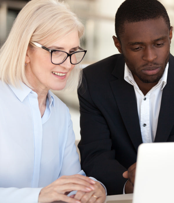 Two coworkers sitting next to each other in front of a laptop